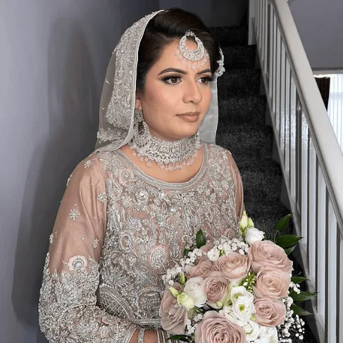 Bride in an embellished blush outfit holding a bouquet